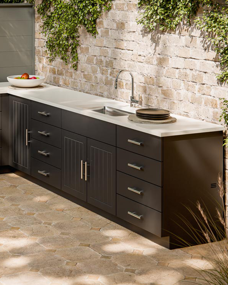 Outdoor kitchens cabinetry with sink, drawers, and durable white countertop.