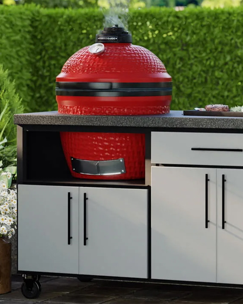 Outdoor kitchens cabinet with red kamado grill and white storage base.