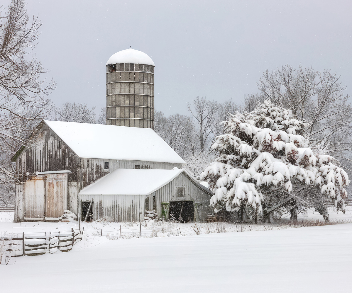 Rural winter barn and silo scene, choosing the best stove for off-grid heat.
